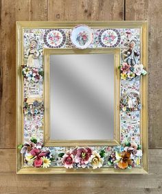 a mirror with flowers on it sitting against a wooden wall