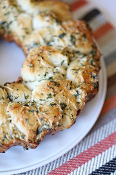 a white plate topped with a bagel covered in cheese and herbs on top of a checkered table cloth