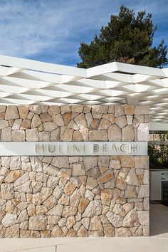 there is a sign that says mullin beach on the side of a stone wall