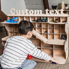 a young boy playing with toys in front of a wooden shelf that says custom text