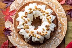 a bundt cake with white frosting and walnuts on top sitting on a plate