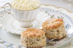 two biscuits on a plate next to a cup of coffee