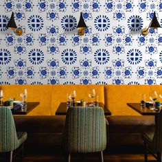 a restaurant with blue and white wallpaper, yellow booths and green chairs in front of it