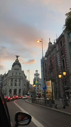 a city street filled with lots of traffic next to tall buildings and lamps on poles