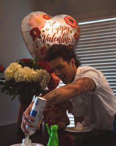 a man pouring water into a cup on top of a table with flowers and balloons in the background