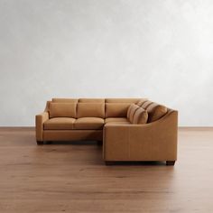 a brown couch sitting on top of a hard wood floor next to a white wall