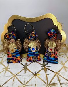 three african dolls sitting on top of a table next to a black board with gold trim