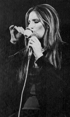 a black and white photo of a woman singing into a microphone