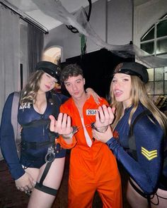 three people dressed in orange and blue posing for the camera with one person wearing an orange jumpsuit