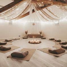 a room filled with lots of yoga mats and pillows on top of wooden flooring