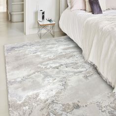 a bedroom with a white bed and gray rug on the floor in front of it