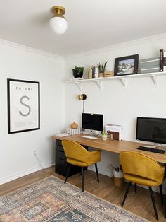 a home office with two computer desks and a rug in front of the window