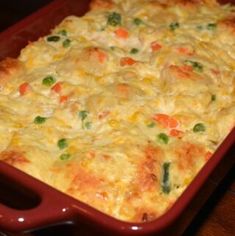 a casserole dish with vegetables and meat in it on a wooden table top