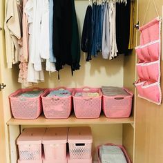 an organized closet with pink baskets and clothes hanging on the wall, along with other storage bins