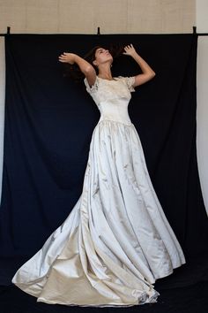 a woman in a long white dress is posing for a photo on a black background