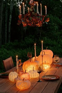 a wooden table topped with lots of lit pumpkins