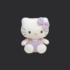 a white hello kitty stuffed animal sitting on top of a black surface with a purple bow around its neck