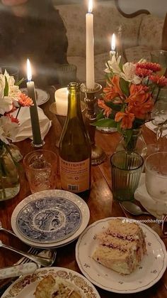 a table topped with plates covered in cake and candles next to bottles of wine on top of a wooden table