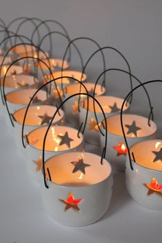 small white bowls with lit candles in them are arranged on a table, surrounded by star - shaped branches