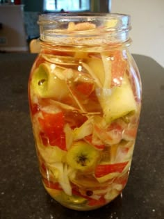 a glass jar filled with sliced fruit on top of a table