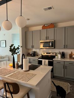 a kitchen with white counter tops and gray cupboards next to a stove top oven