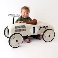 a young boy sitting in a toy race car with the number 1 on it's side