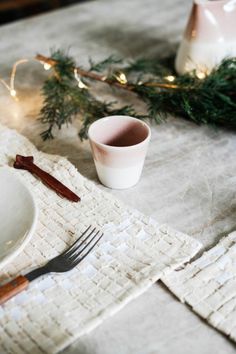 a place setting with white dishes and greenery