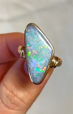 Discover timeless elegance with our 18ct Yellow Gold Solid Opal Ring, a true masterpiece in craftsmanship and design. Handcrafted from luxurious 18-carat yellow gold, this ring showcases a mesmerizing asymmetric opal centerpiece, exuding natural iridescence and a kaleidoscope of colors with every movement. The opal, renowned for its captivating play-of-color, is securely set within a sleek and modern design, creating a striking contrast against the warm glow of the gold band. The minimalist yet Luxury Opal Ring For Gift, Opal Rings With Polished Finish For Formal Occasions, Formal Opal Rings With Polished Finish, Formal Opal Ring With Polished Finish, Luxury Opal Ring With Cabochon Cut, Luxury Opal Cabochon Rings, Fine Jewelry Yellow Gold Opal Ring With Polished Finish, Polished Yellow Gold Opal Ring, Elegant Hallmarked Opal Ring