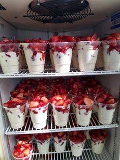 there are many plastic cups with strawberries in them on the shelf next to each other