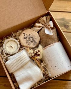 an open box with some items in it on a wooden table next to a candle