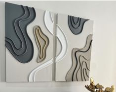 two abstract paintings on the wall next to a vase with gold and silver flowers in it