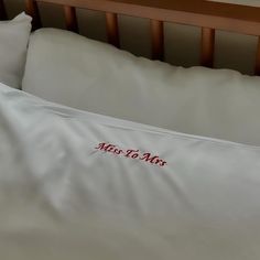 a white pillow with the words miss to mrs written on it in red ink is laying on a bed