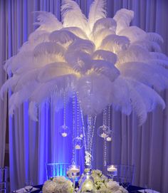 a tall centerpiece with white flowers and feathers