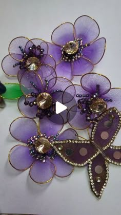 three purple flowers are sitting on top of each other, with beads and sequins