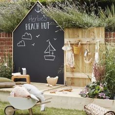 a blackboard with writing on it in the middle of some grass and wooden furniture