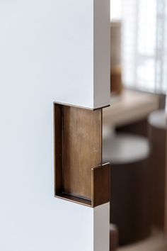 a close up of a door handle on a white wall with chairs in the background