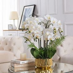 a vase filled with white flowers sitting on top of a table next to a couch