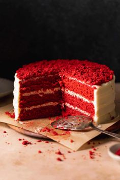 a red velvet cake with white frosting and sprinkles on the side