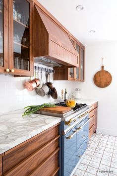 a kitchen with marble counter tops and wooden cabinets, along with hanging utensils