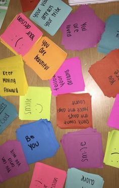 colorful sticky notes with words written on them sitting on top of a wooden table covered in paper