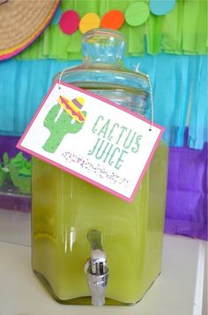 a green beverage dispenser sitting on top of a table next to a straw hat