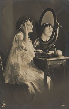 an old photo of two women sitting at a table in front of a large mirror