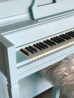 a white piano sitting on top of a wooden floor next to a fur covered bench