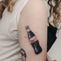 a woman's arm with a bottle of coca cola on the left side of her shoulder