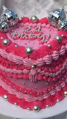 a heart shaped cake decorated with pink icing and silver decorations