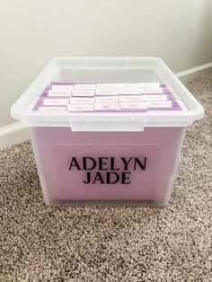 a plastic storage box with labels on it sitting on the floor next to a wall