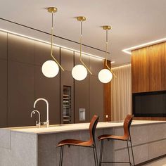 a kitchen with two bar stools and three lights hanging from the ceiling above it