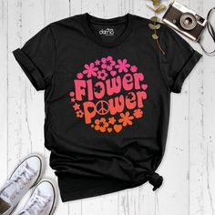 Step into a world of groovy style with our Flower Hippie Shirt, the perfect addition to any boho wardrobe. Embrace the essence of the '60s and '70s with our Flower Power Shirt, designed to channel retro vibes and bring back that flower child spirit. This floral boho shirt is a true standout, featuring a unique and rich design that will turn heads wherever you go. Our Power Girls Shirt is all about empowering women with its strong vibrant and vibrant statement. Join the hippie party and celebrate life's natural beauty with our Wildflower Shirt, a perfect blend of bohemian charm and free-spirited elegance. The Vintage Flower Shirt is a nod to timeless fashion, capturing the essence of a bygone era. Whether you're strolling through music festivals, exploring nature, or simply enjoying a sunny Hippie Letter Print Tops For Spring, Groovy Graphic Print Summer Shirt, Hippie Tops With Funny Print For Spring, Spring Hippie Top With Funny Print, Hippie Top With Funny Print For Spring, Spring Hippie Short Sleeve Shirt, Hippie Short Sleeve Shirt For Spring, Retro Funny Print Shirt For Spring, Retro Shirt With Funny Print For Spring