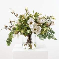 a vase filled with white flowers and greenery