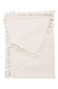 a white blanket with pom poms on the bottom and fringes around it